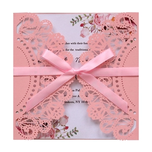 Detailed laser-cut pink lace invitation card with a silk bow and floral printed insert