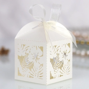 Macro view of white laser-cut hibiscus candy box with detailed leaf patterns and silk ribbon