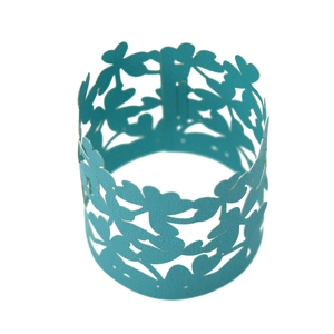 Detail of cyan laser-cut four-leaf clover napkin ring with hollowed floral paper texture
