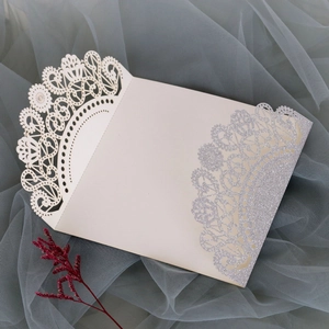 Detailed laser-cut lace edge and silver glitter on ivory wedding invitation card cover