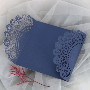 Detail of laser-cut navy blue lace invitation cover on soft tulle with dried floral decor