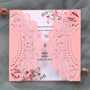 Detail of pink laser cut lace wedding invitation with floral insert on mesh background