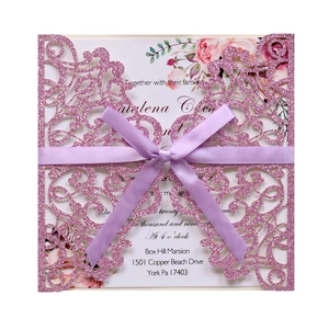 Detail of pink glitter laser cut wedding invitation with lavender ribbon and floral insert