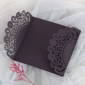 Intricate laser-cut lace pattern detail on deep purple wedding invitation envelope