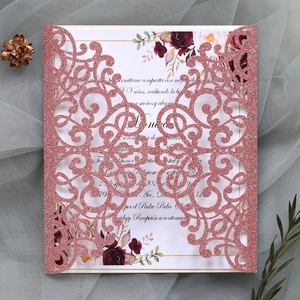 Macro detail of laser-cut rose gold glitter wedding invitation with floral insert