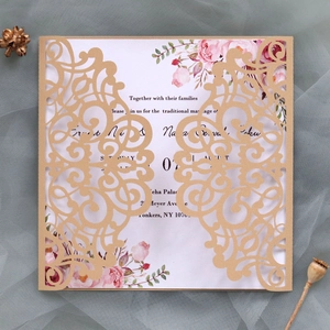 Détail de l'invitation de mariage découpée au laser avec dentelle dorée et carte fleurie