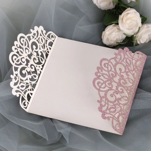 Detail of laser-cut wedding invitation with pink glitter and elegant lace patterns