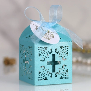 Close-up of laser-cut blue favor box with cross pattern, ribbon, and thank you tag