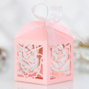 Detailed laser-cut rose patterns on light pink wedding favor box with ribbon