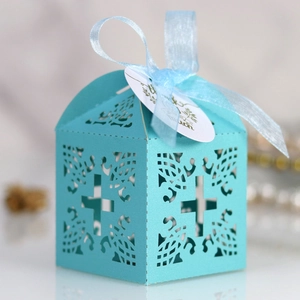 Macro view of light blue laser-cut cross gift box with ribbon and thank you tag