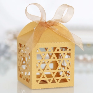 Macro shot of gold laser-cut gift box with hollow patterns and sheer ribbon