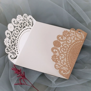 Detail of laser-cut lace invitation cover featuring rose gold glitter and ivory finish