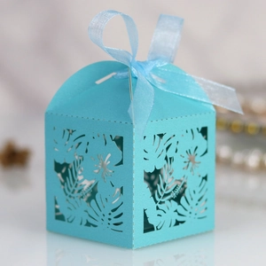 Detail of laser-cut floral pattern on sky blue wedding candy box with a chiffon bow