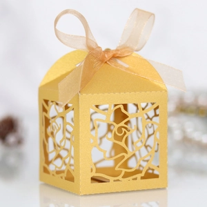 Detail of gold laser-cut rose hollow favor box with matching organza ribbon bow
