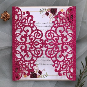 Close-up of laser-cut glitter paper wedding invitation with floral inner card