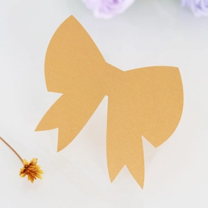 Detail of golden glitter bow place card with metallic texture on white floral background