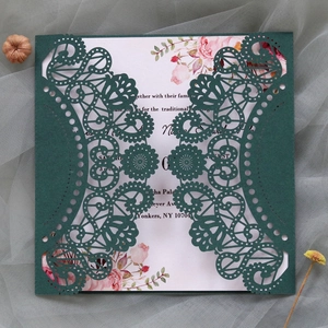 Detailed laser-cut dark green lace invitation set with floral inner card on silk background