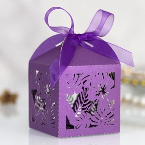 Close-up of laser-cut purple gift box with tropical leaf patterns and ribbon