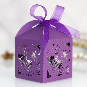 Close-up of purple laser-cut tropical leaf patterns and ribbon on a square gift box