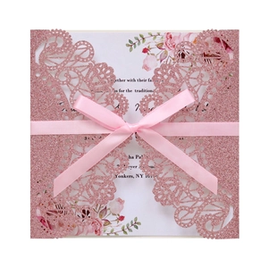 Detail of rose gold glitter laser-cut lace invitation with floral inner card and pink ribbon