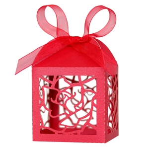 Close-up of laser-cut rose patterns on a red wedding favor box with a satin ribbon bow