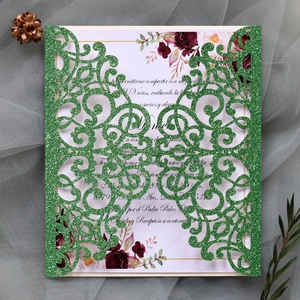 Close-up of green glitter laser-cut invitation envelope with floral card insert