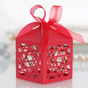 Macro shot of red laser-cut candy box with star patterns and matching organza ribbon