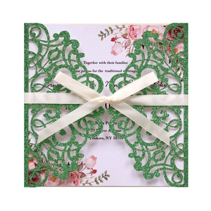 Macro detail of laser-cut green glitter wedding invitation with satin bow and floral insert