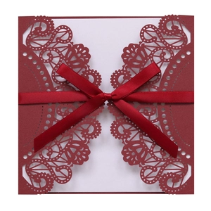 Detail of burgundy laser-cut lace invitation with silk ribbon and white inner card
