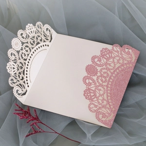 Detailed view of laser-cut lace wedding invitation pocket with pink glitter texture