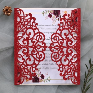 Macro detail of laser-cut red glitter wedding invitation with floral inner card