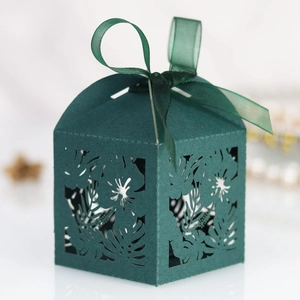 Detail of laser cut tropical leaf pattern on dark green candy box with a green ribbon