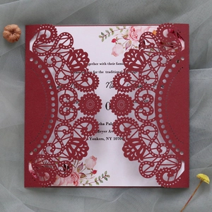 Close-up of laser-cut burgundy lace wedding invitation with floral printed inner card