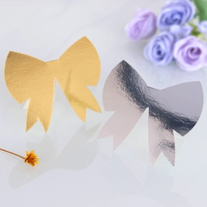 Detail view of laser-cut gold and silver 3D bow place cards with a metallic mirror finish