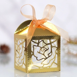Detailed macro view of laser-cut rose patterns on the golden favor box with ribbon