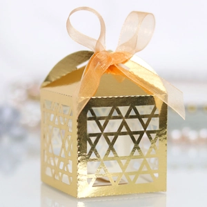 Close-up of golden hollow star candy box with a shimmering champagne ribbon bow
