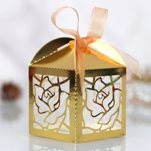 Detail of laser-cut rose hollow gift box in metallic gold with orange ribbon bow