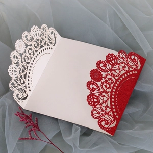 Close-up of laser-cut lace floral pattern with red glitter on cream white card