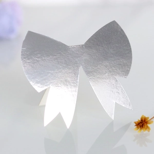 Close-up of laser-cut silver 3D bow place card with metallic finish for weddings