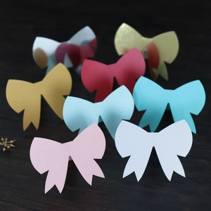 Close-up of assorted laser-cut 3D bow place cards in glittery cardstock colors