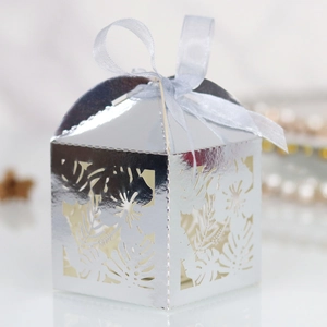 Macro shot of laser-cut hibiscus flower and leaf pattern on silver metallic favor box