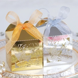 Macro view of laser-cut gold and silver favor boxes with elegant leaf patterns