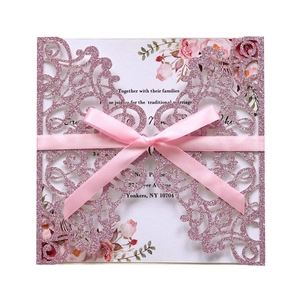 Detail of pink laser-cut floral wedding invitation with glitter finish and silk bow