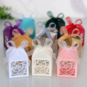 Detail of laser-cut rose patterns on wedding favor boxes with elegant silk ribbon bows