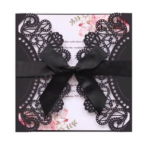 Detailed laser-cut hollow lace design on black wedding invitation with satin ribbon bow