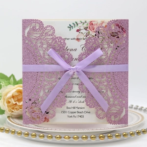 Detailed laser-cut glitter purple wedding invitation with silk ribbon on a decorative plate