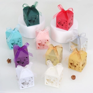 Macro detail of laser-cut floral favor boxes featuring delicate hollow leaf patterns and ribbons