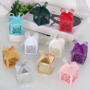 Close-up of laser-cut rose hollow candy gift boxes with ribbon bows in various colors
