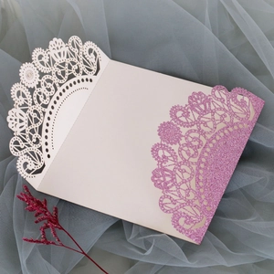 Macro shot of laser-cut lace pattern with pink glitter on wedding invitation cover