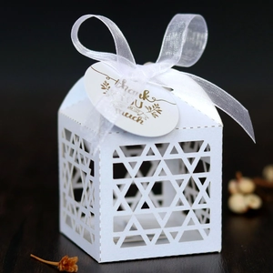 Detail of white laser-cut star favor box with Thank You tag on dark wood background